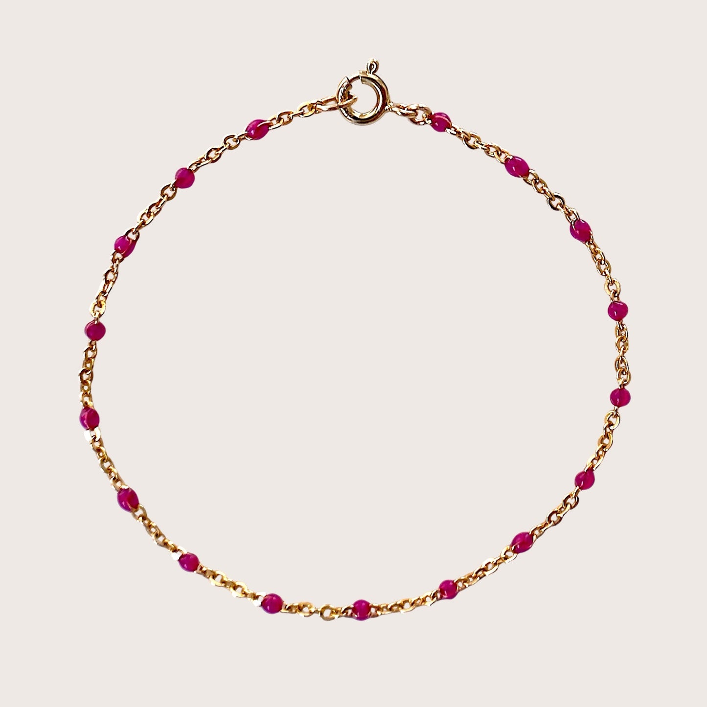 Gold bracelet with pink beads on a light pink background