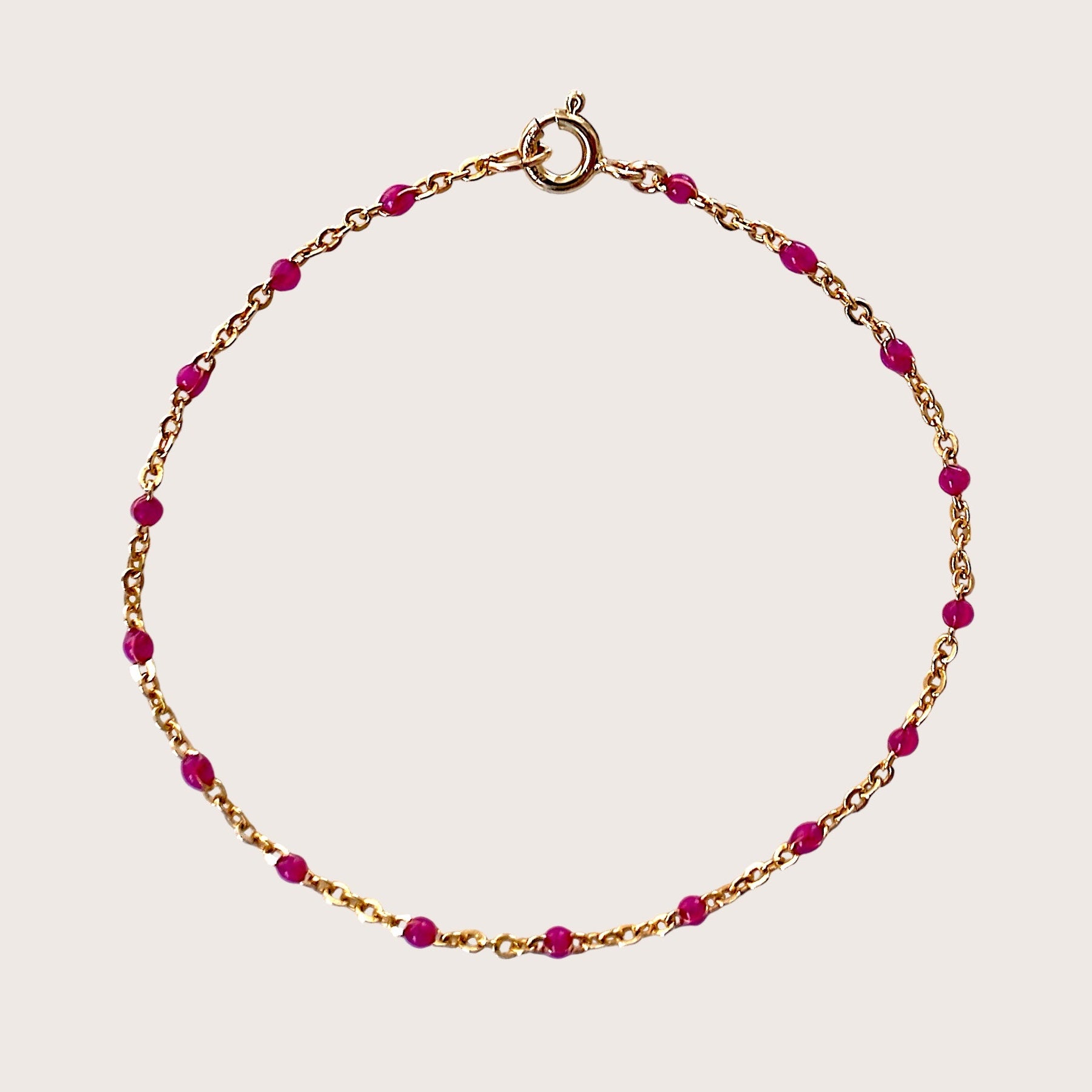 Gold bracelet with pink beads on a light pink background