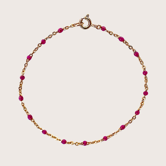 Gold bracelet with pink beads on a light pink background