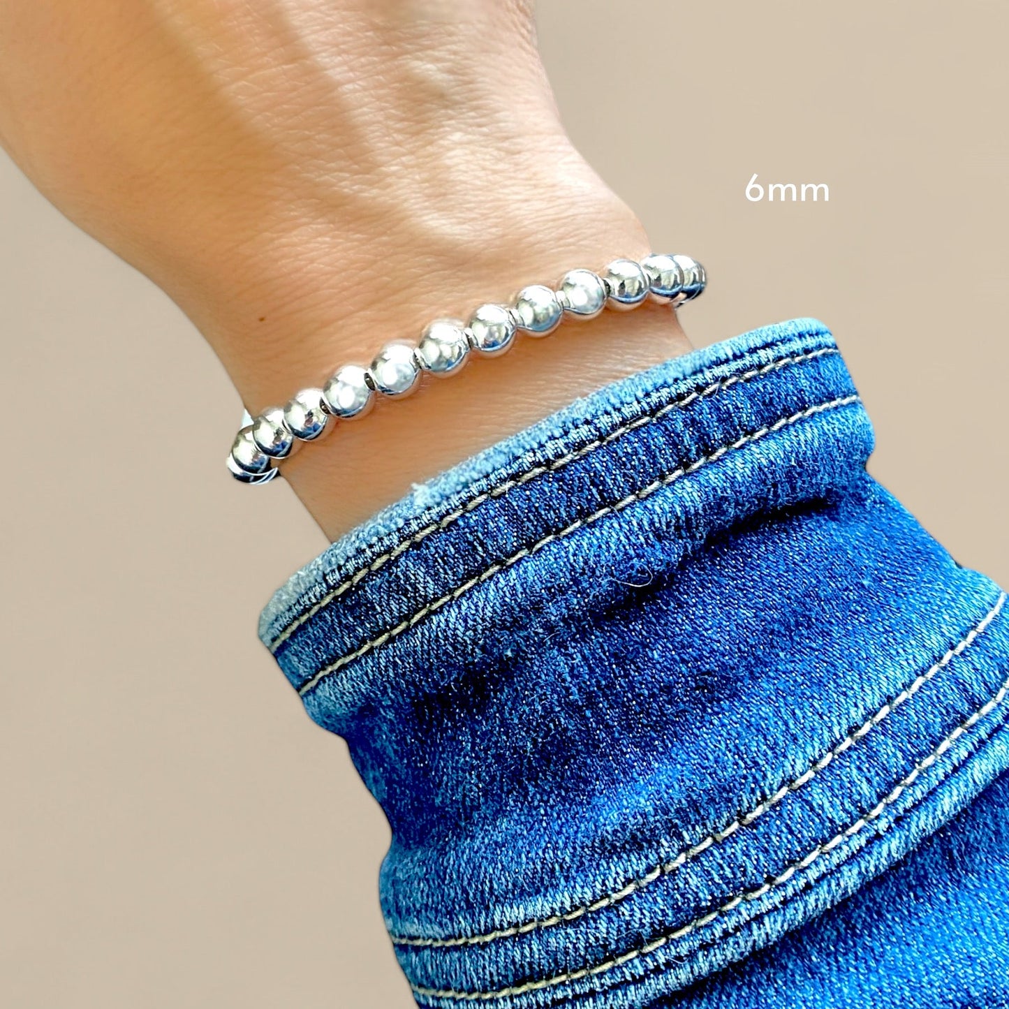 A 6mm silver beaded chain bracelet with a lobster claw closure on a model 