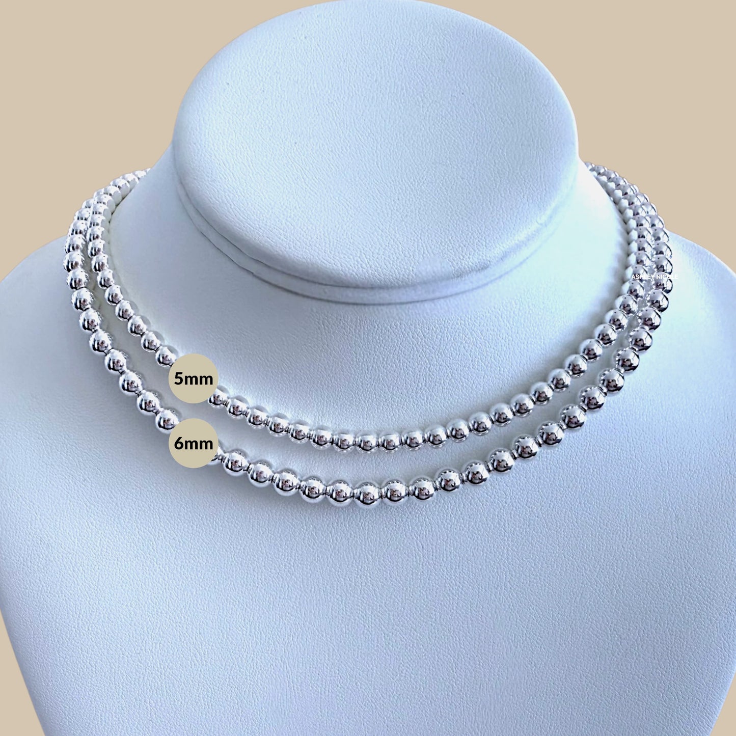 Silver beaded necklace on a mannequin with size labels '5mm' and '6mm'.