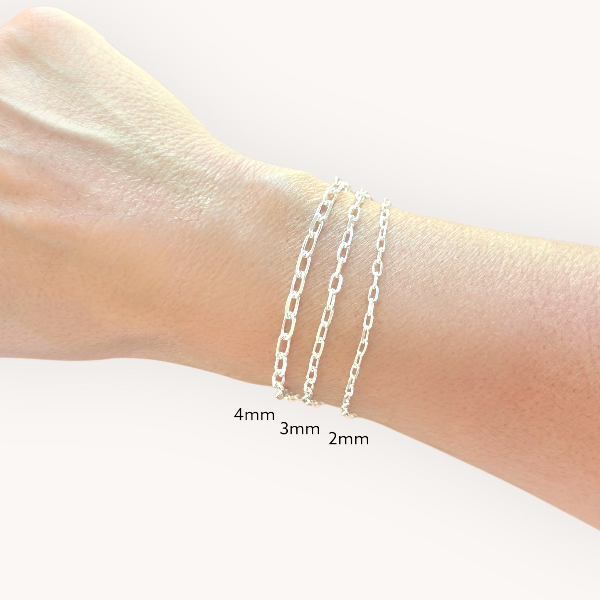 Silver chain bracelets on a wrist with size labels
