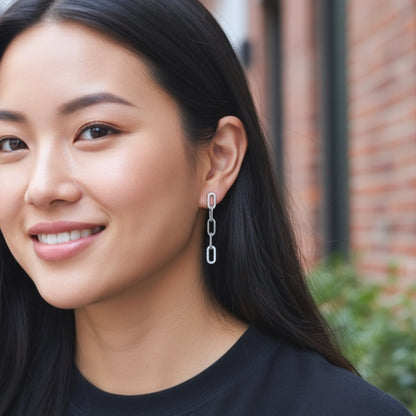 Model wearing sterling silver cz chain drop earrings earring with a blurred brick wall background