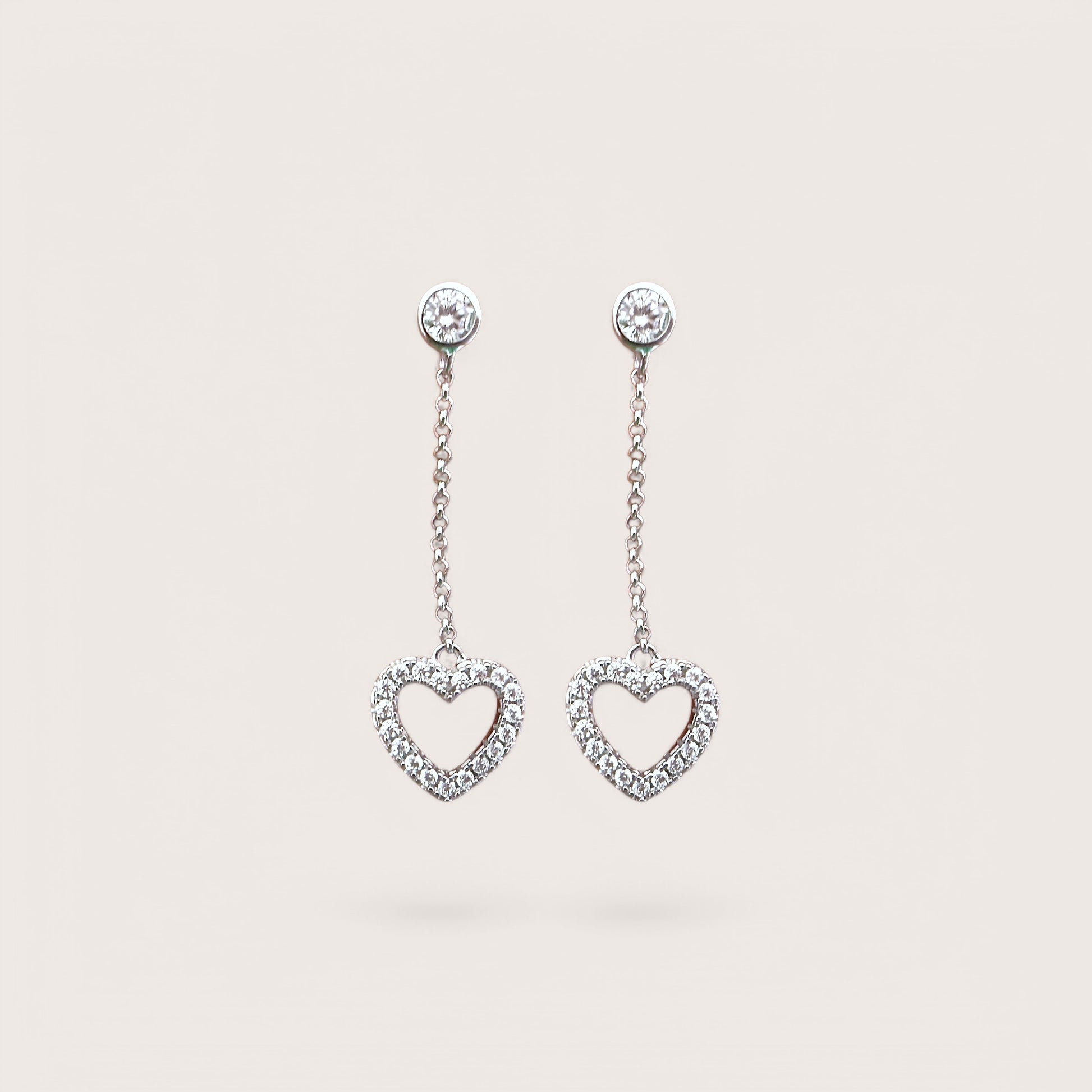 A pair of sterling silver dangle earrings with cubic zirconia in a heart shape design.