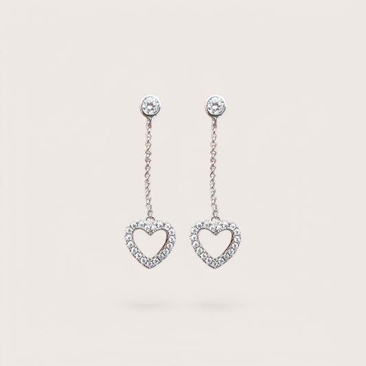 A pair of sterling silver dangle earrings with cubic zirconia in a heart shape design.