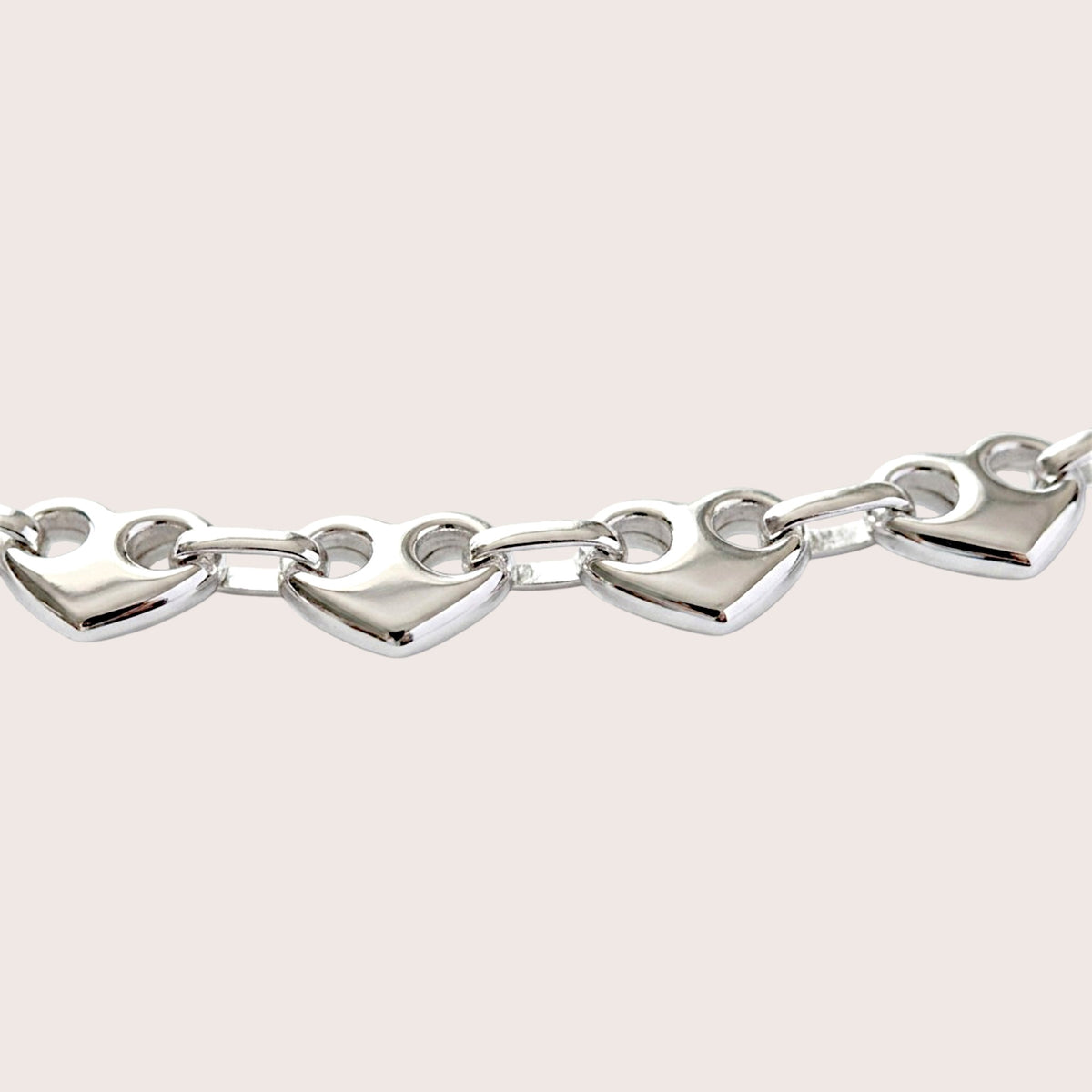 Close-up of polished puffed heart links with two circular openings joined by oval connectors.