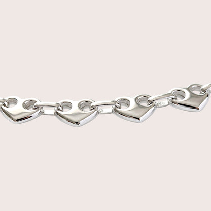 Close-up of polished puffed heart links with two circular openings joined by oval connectors.