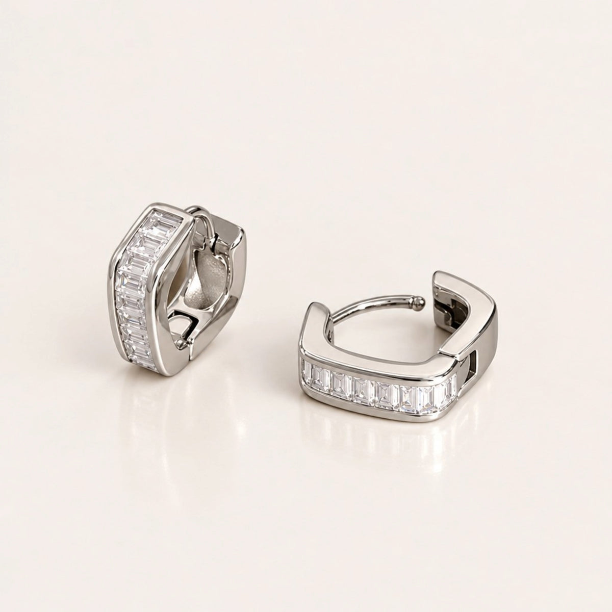 Silver-tone hex baguette huggie hoop pair with one upright and one lying open to show the curved post and hinged closure.