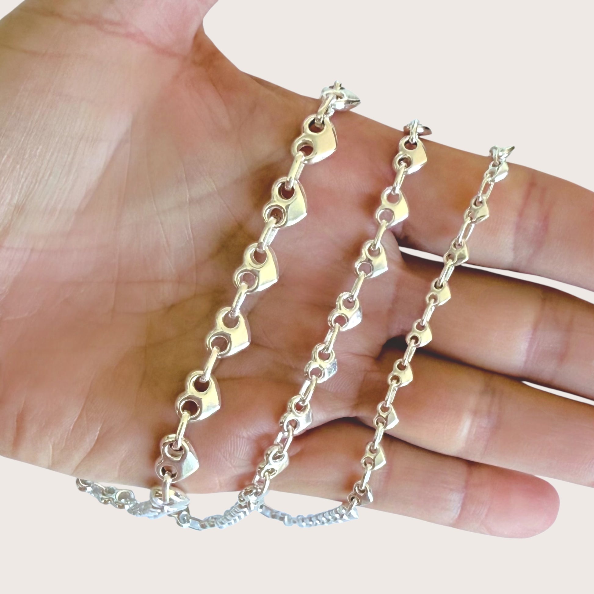Silver chain held in a hand against a light background