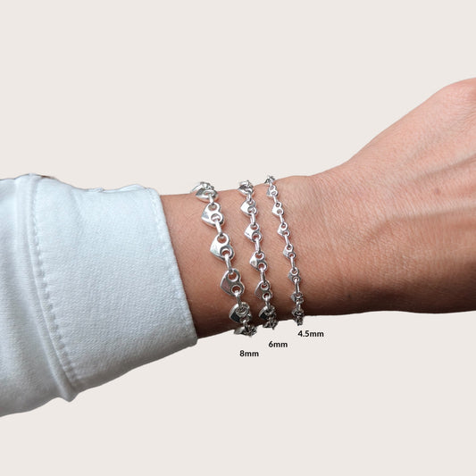 Heart-shaped puffed mariner chain bracelet in 925 sterling silver shown on a model's wrist, custom-fitted, bold and polished finish