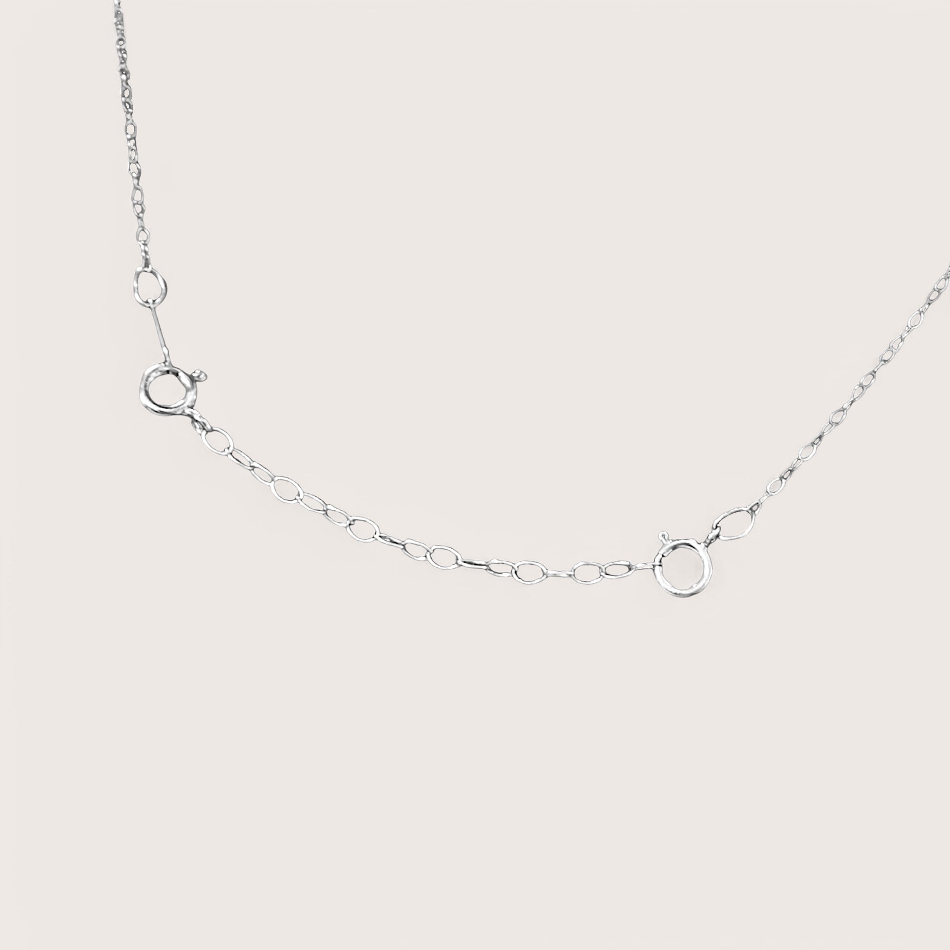 Close-up detail of dainty silver cable chain links and secure attachments with a bright mirror silver finish. Displays how to attach to necklace to make it longer.