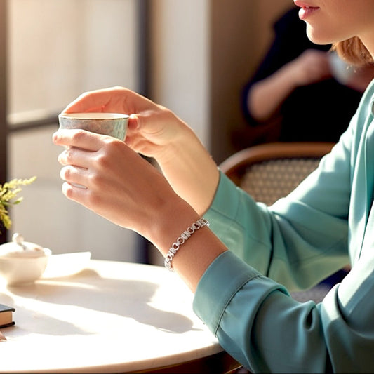 925 Sterling  Silver Pave CZ U Link chain bracelet on a light gray  Person holding a cup of coffee in a cozy indoor setting