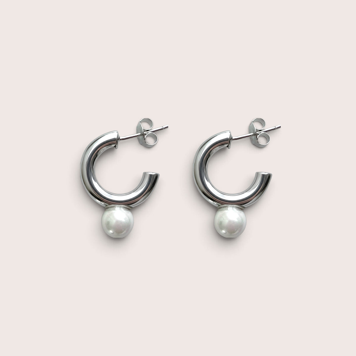 Pair of silver open C tube hoop earrings with white pearls, lying flat on an ivory background.