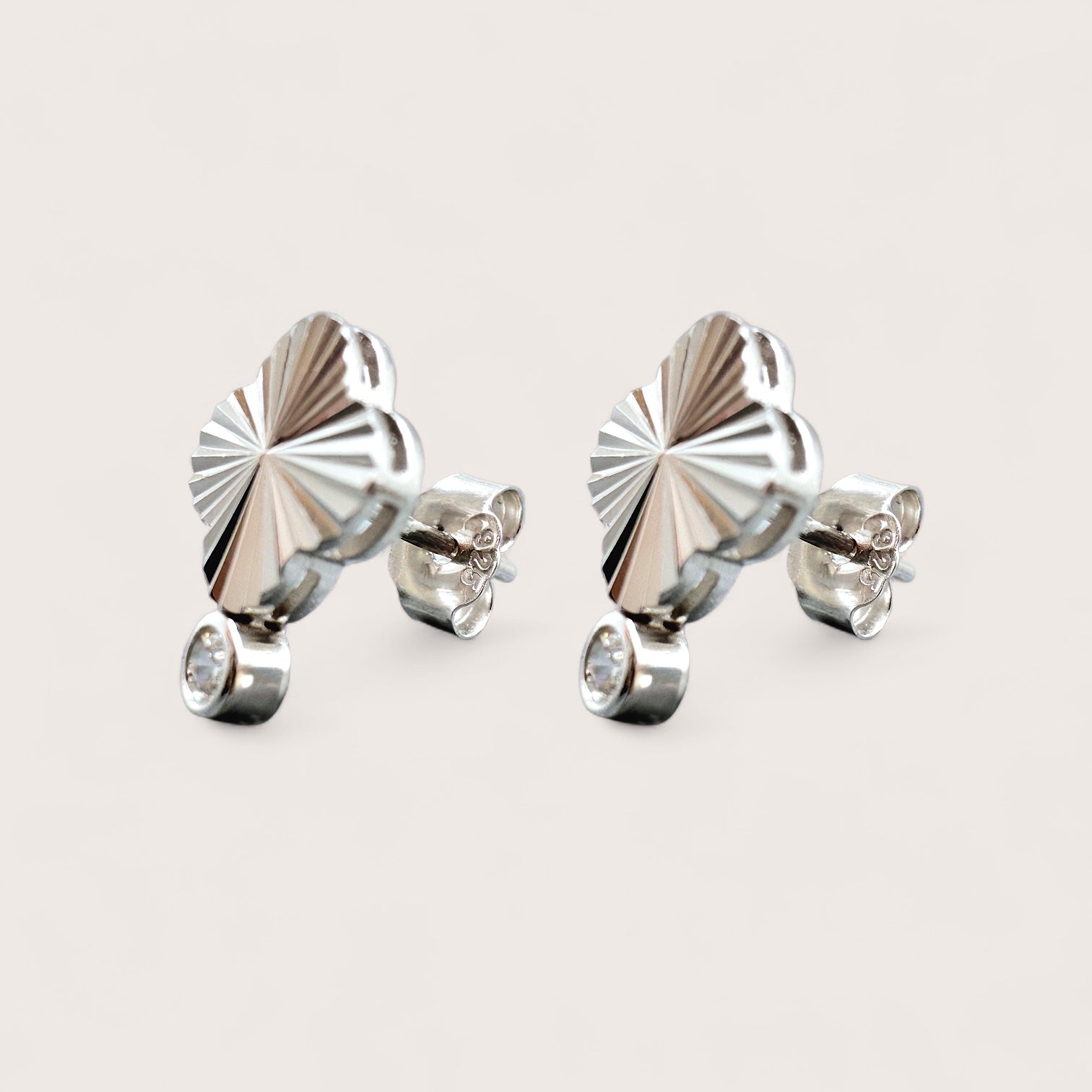 Pair of silver earrings with a diamond cut pattern geometric 4-leaf clover design and a sparkling solitaire cubic zirconia gemstone.