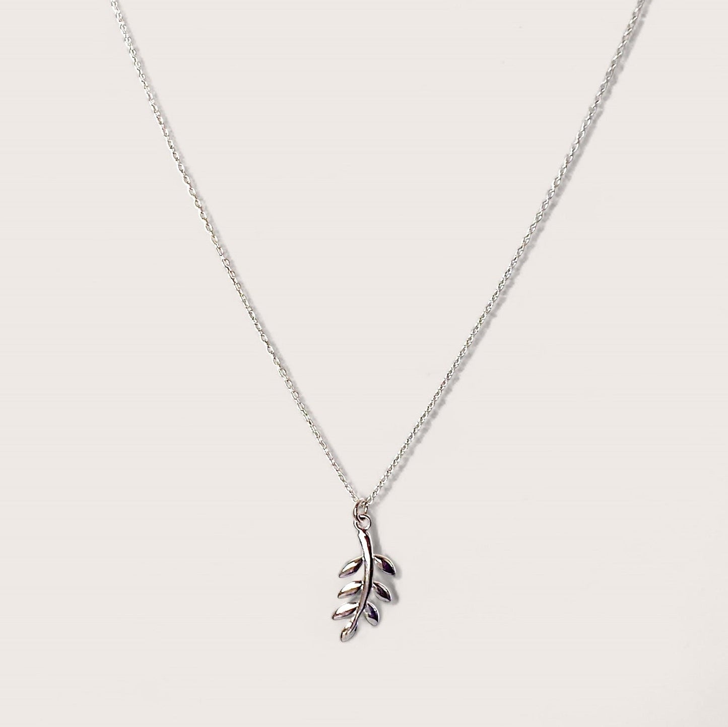 A close up of a silver leaf and branch pendant necklace which symbolizes peace, harmony in a solid sterling silver.