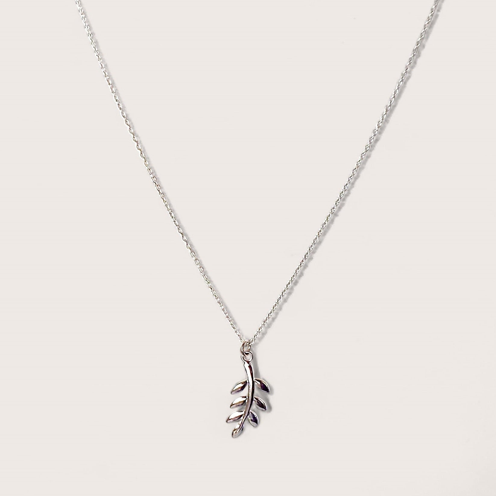 A close up of a silver leaf and branch pendant necklace which symbolizes peace, harmony in a solid sterling silver.