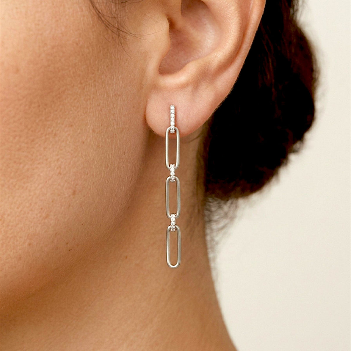 Close up of a person wearing Silver Paperclip Chain Dangle Drop Earrings with sparkling CZ links