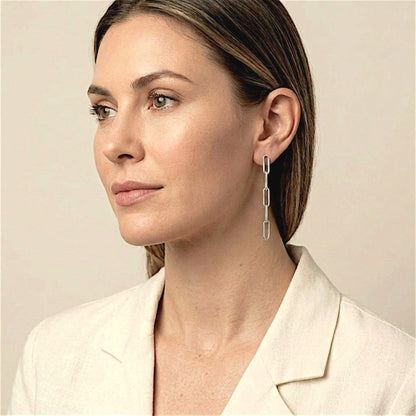 Model in an ivory jacket wearing sterling silver paperclip dangle earrings, with her hair tucked behind her ear.