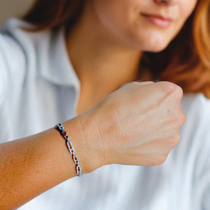 Close-up of a person wearing a silver chain bracelet on a blurred background