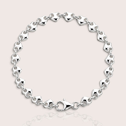 Polished silver puffed heart link bracelet arranged in a circle with the lobster clasp visible.