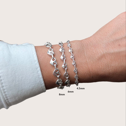 Heart-shaped puffed mariner chain bracelet in 925 sterling silver shown on a model's wrist, custom-fitted, bold and polished finish
