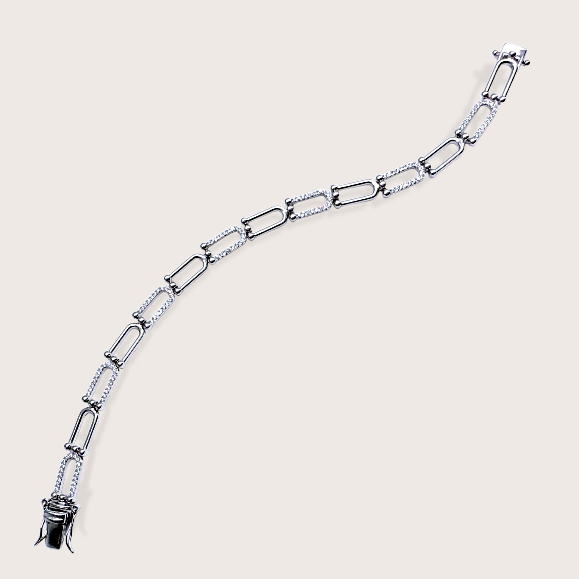Image of entire bracelet including claps Silver chain bracelet on a light beige background