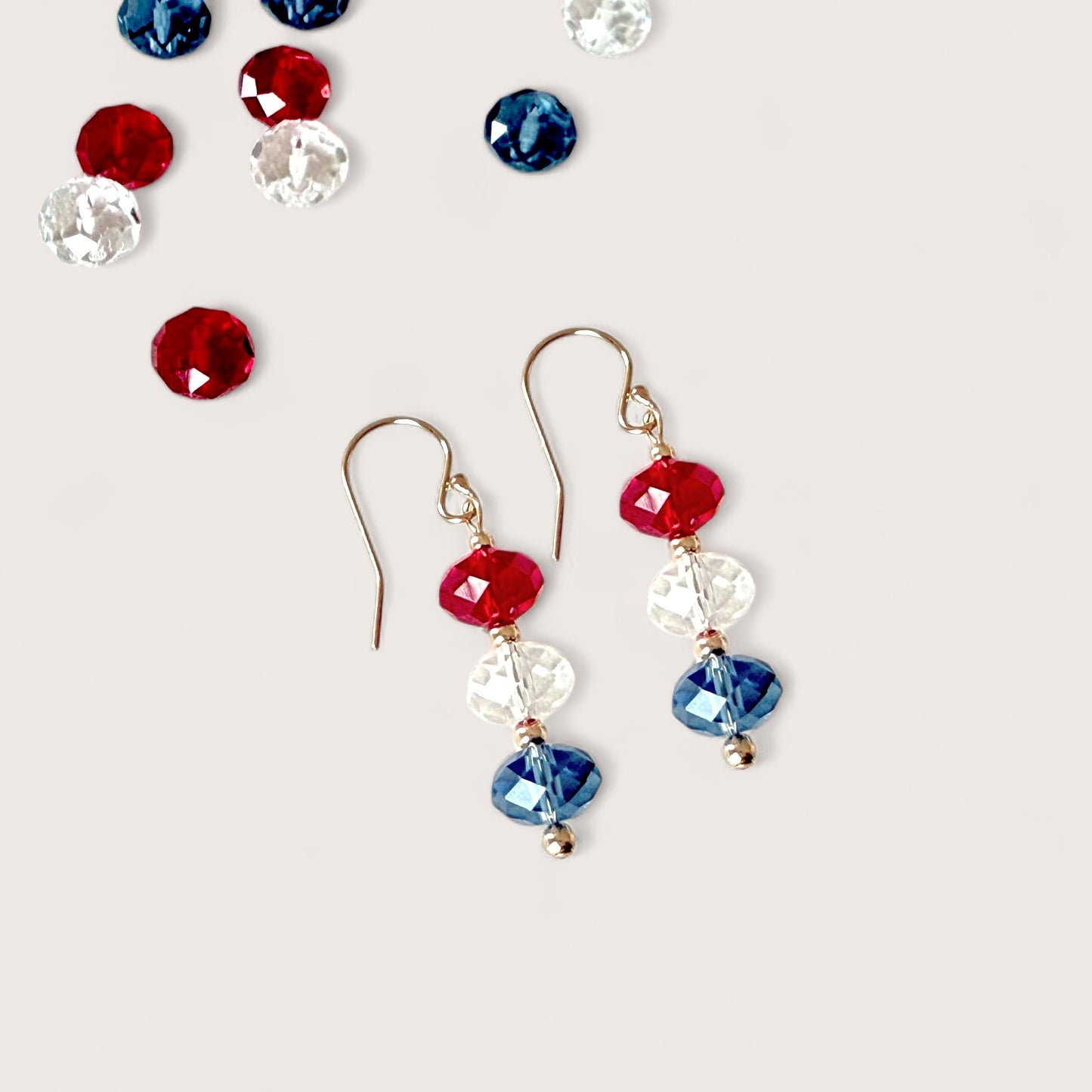 Side profile studio hero shot showing the exact scale for authentic red white and blue Swarovski crystal patriotic dangle earring on 14k gold-filled wire by Ashley Nicole Jewelry.