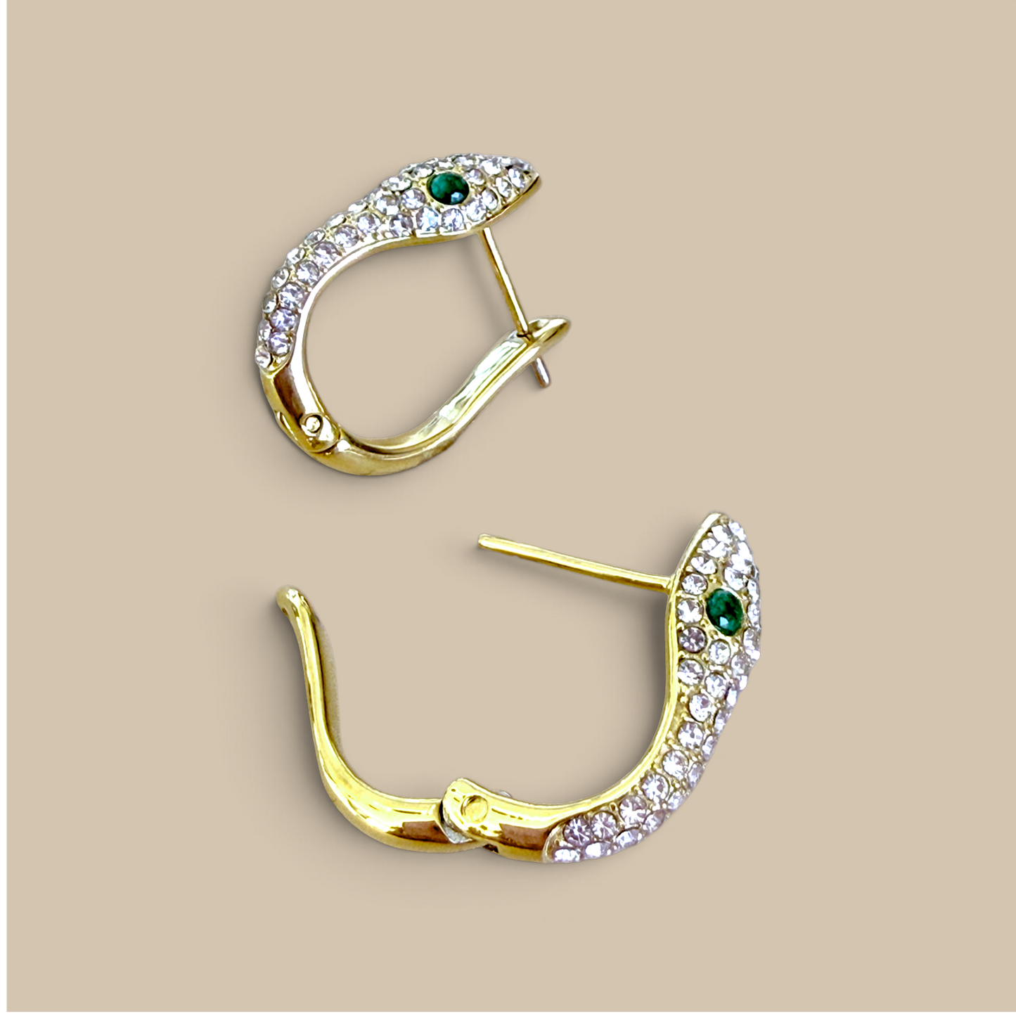 A top-down flat lay perspective of the two 18K gold PVD-finished snake huggie earrings, showing the full curved silhouette and post-back closure mechanism.