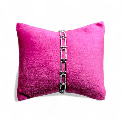 Silver bracelet on a pink pillow with a white background