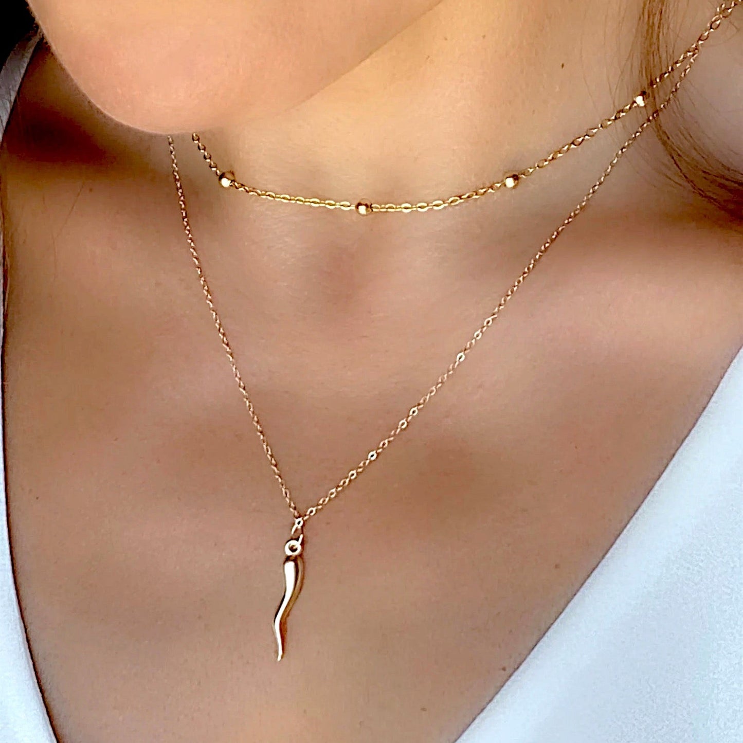 Model wearing both the large 14K yellow gold filled Italian horn necklace layered together to show a layered ear-to-chest look