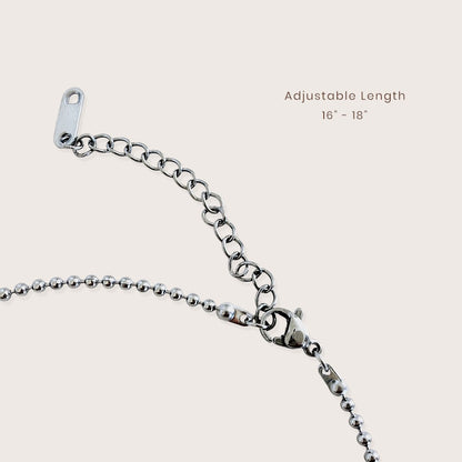 Close-up of a silver metal chain necklace extender with a lobster clasp and adjustable tag, shown on a light beige background with text reading 'Adjustable Length 16" - 18"'.