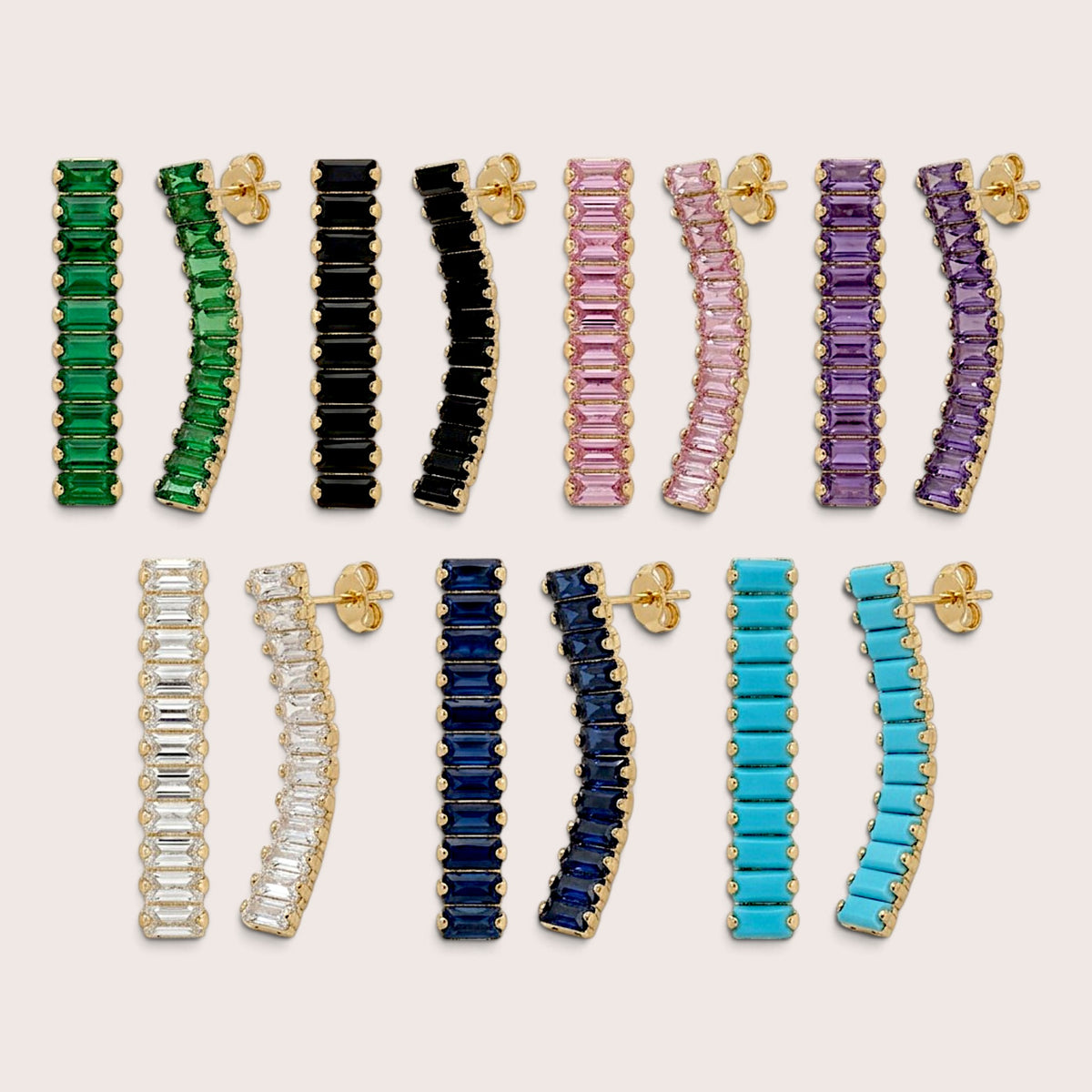 Seven pairs of gold-tone baguette drop earrings in green, black, pink, purple, clear, navy blue, and turquoise blue, with posts and butterfly backs visible.