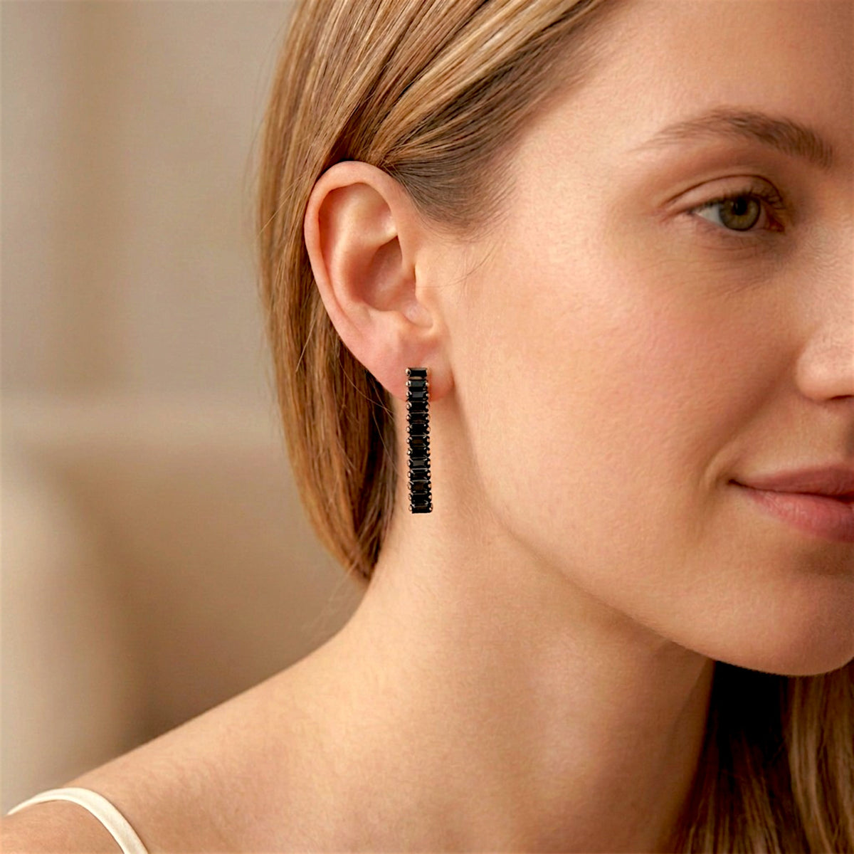 Close-up of a woman wearing a black baguette CZ drop earring with gold-tone settings.