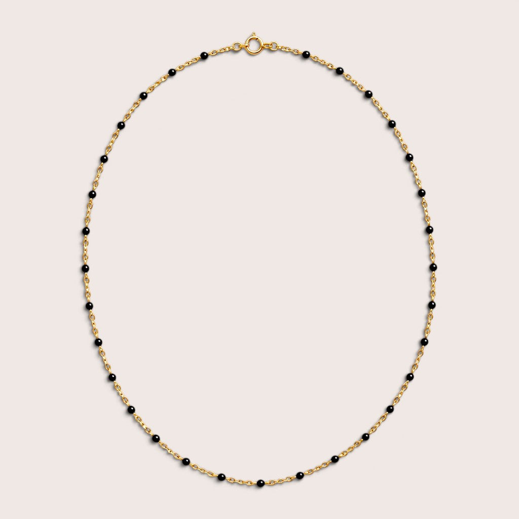 Black enamel station beads spaced along a gold-filled necklace