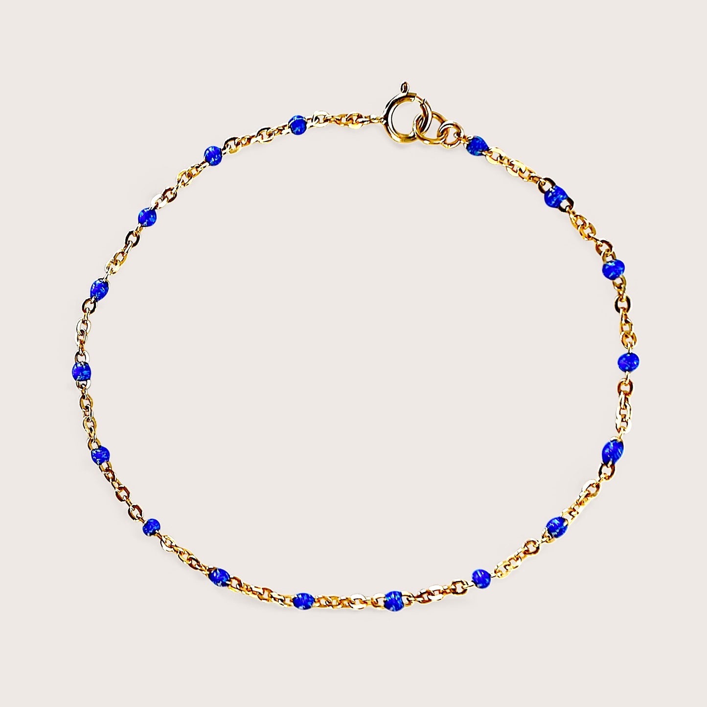 Flat lay image of a royal blue and gold satellite chain bracelet in solid 14k gold filled, waterproof and tarnish resistant gold no fade by Ashley Nicole Jewelry 