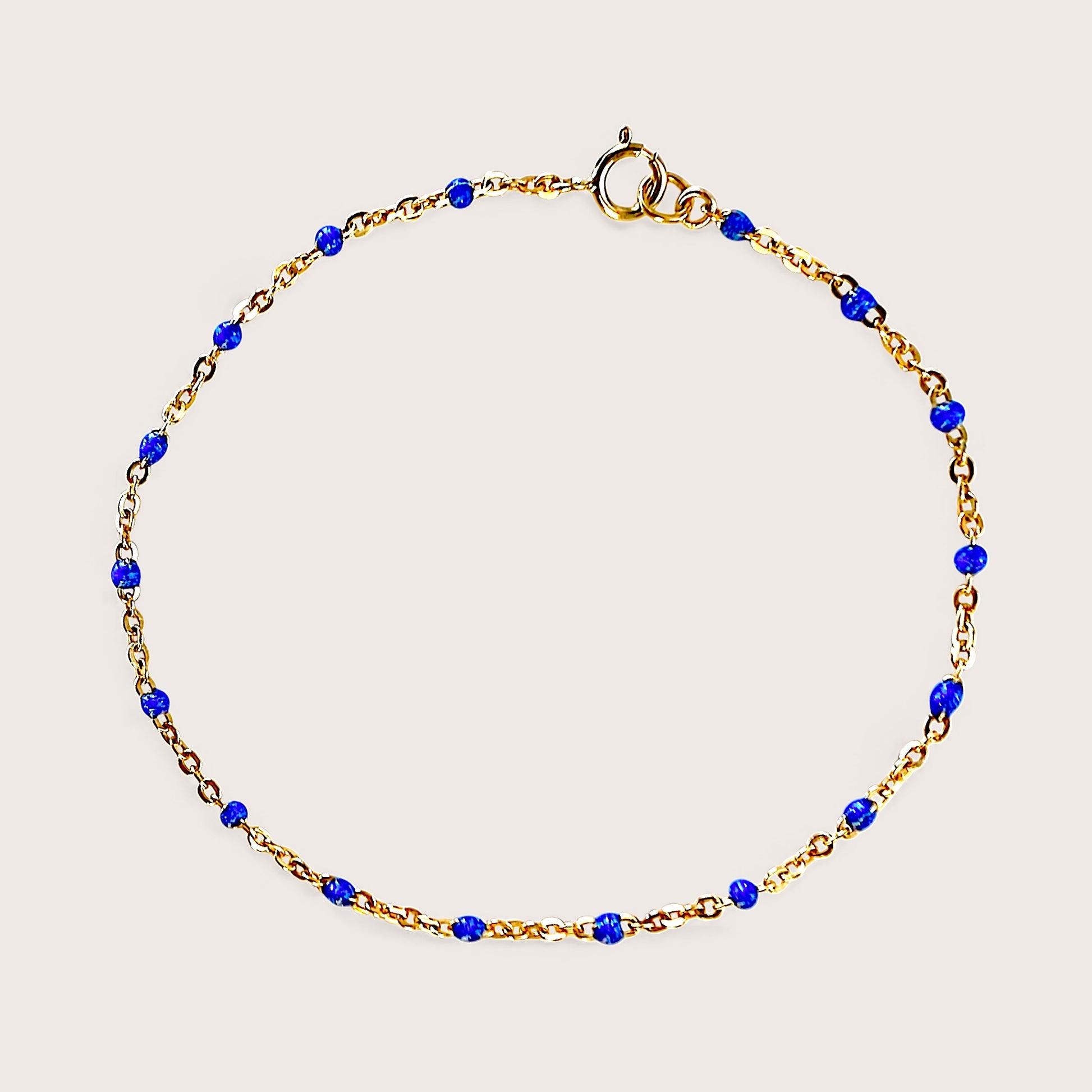 Flat lay image of a royal blue and gold satellite chain bracelet in solid 14k gold filled, waterproof and tarnish resistant gold no fade by Ashley Nicole Jewelry 