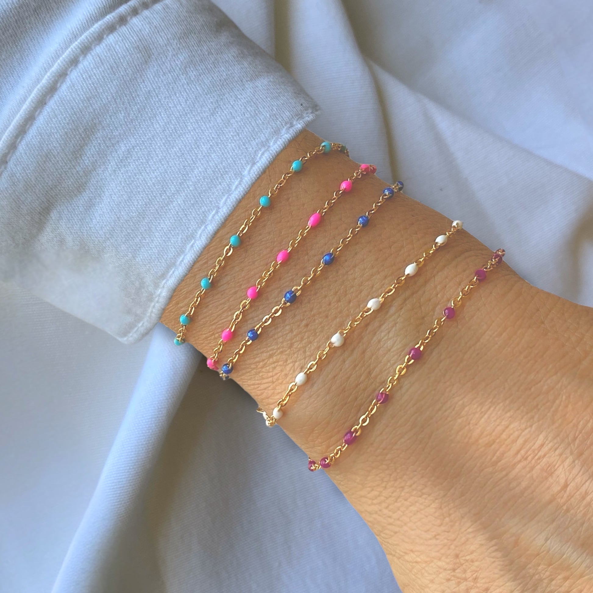 Minimalist wrist stack featuring the colorful enamel satellite chain bracelets stacked by Ashley Nicole Jewelry 