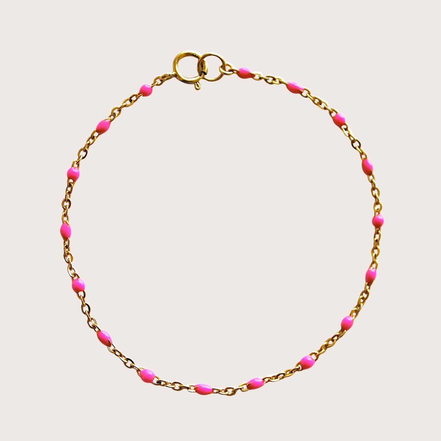 Flat lay view of a bright pink enamel beaded satellite bracelet in 14K gold filled hardware.