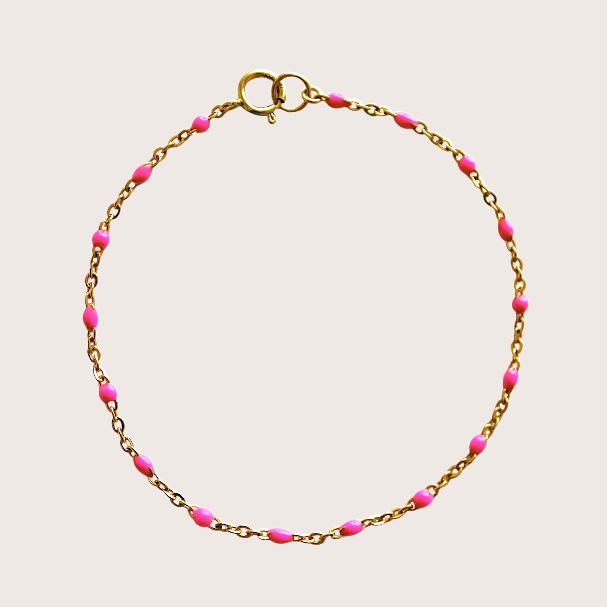 Flat lay view of a bright pink enamel beaded satellite bracelet in 14K gold filled hardware.