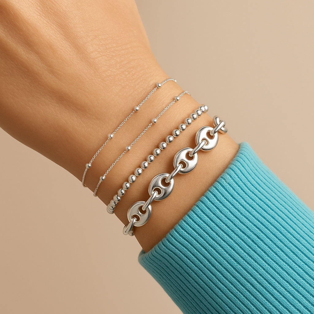 Model wearing the 8mm chunky Italian solid sterling silver puffed mariner coffee bean link bracelet styled in a stack by Ashley Nicole Jewelry