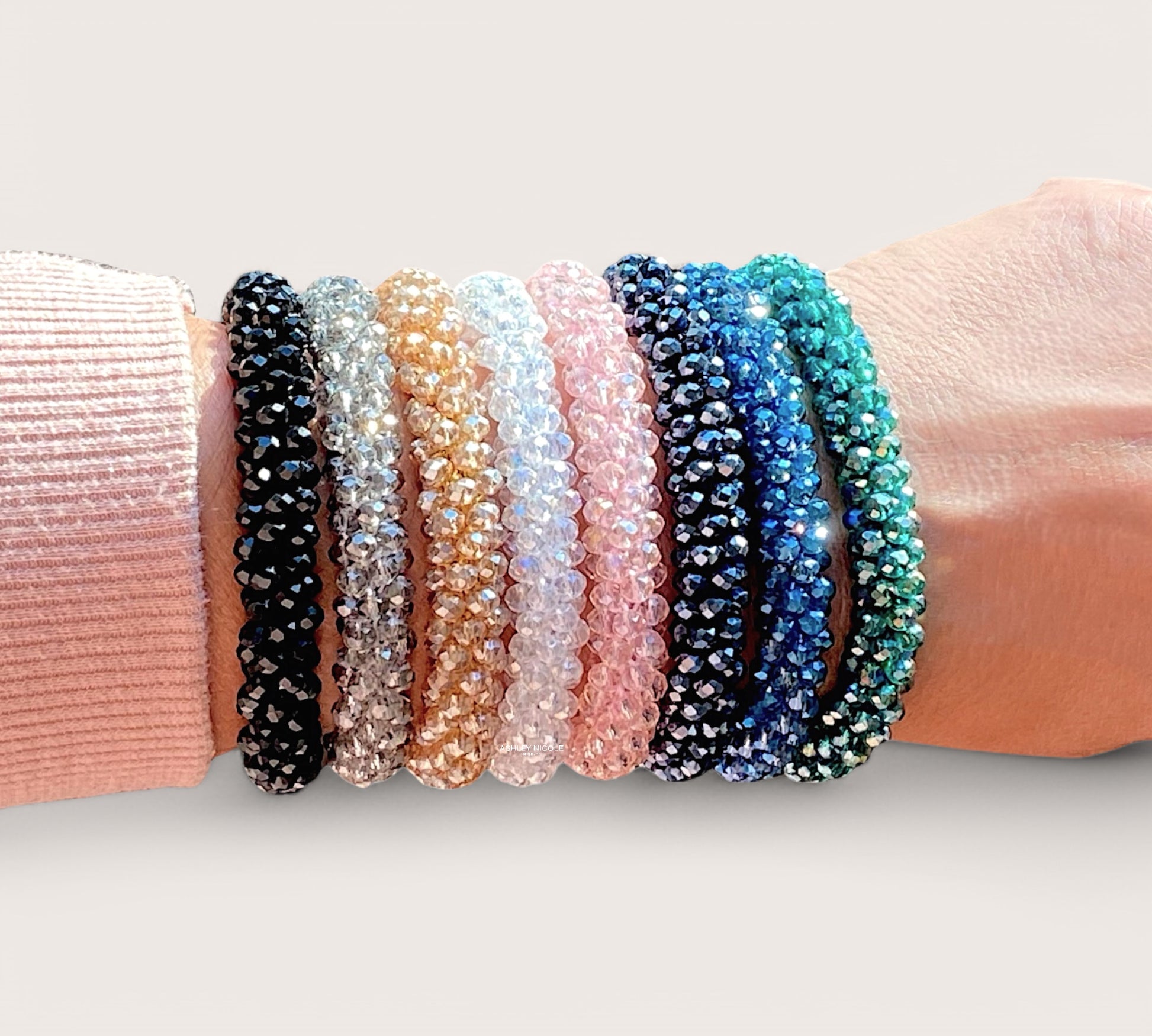Close-up lifestyle photo of a model wearing a waterproof crystal bead hair tie as a stackable wrist band band paired with other colors by Ashley Nicole Jewelry.