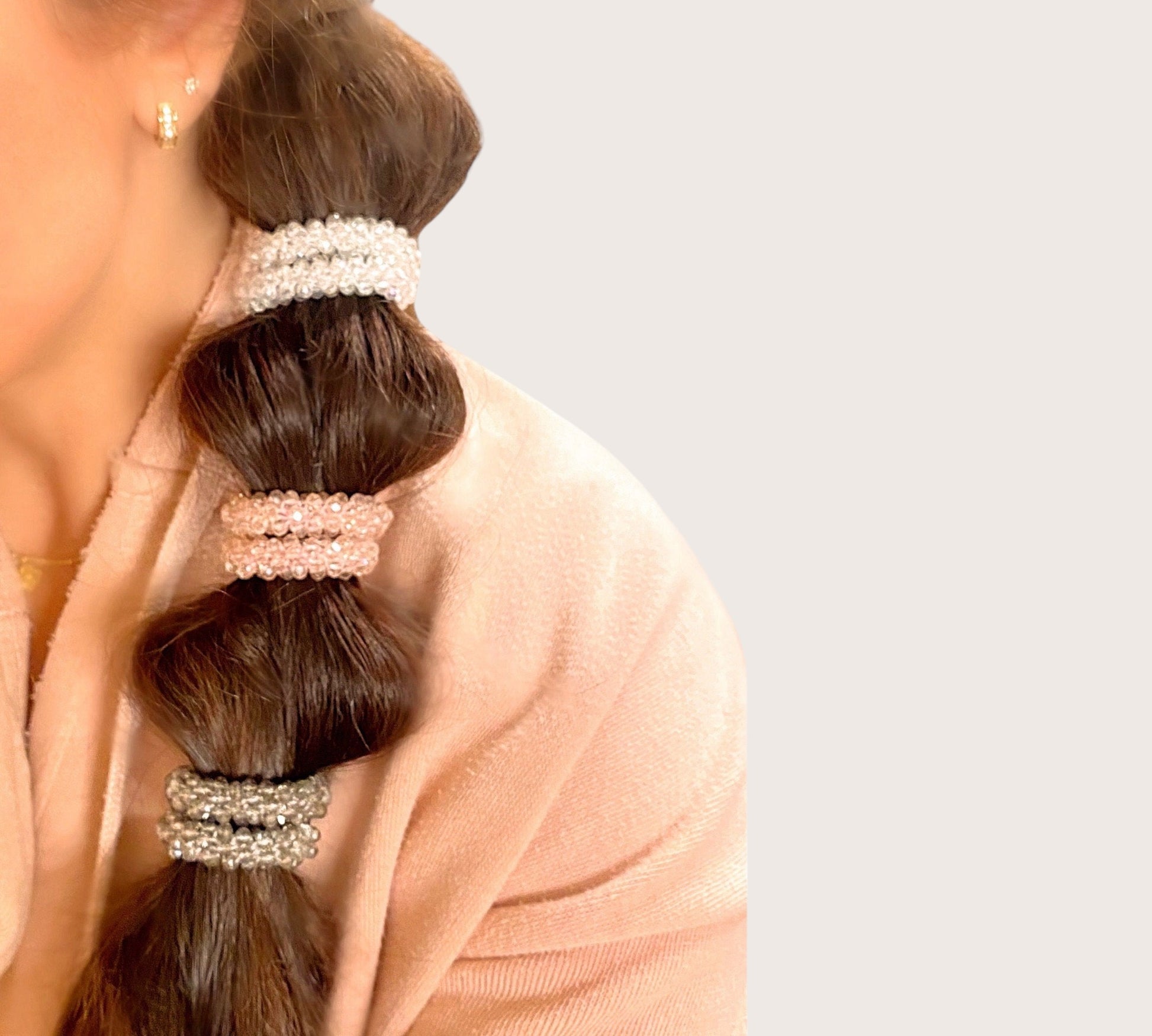 A close-up lifestyle look at the Ashley Nicole Jewelry crystal beaded hair tie securing a sleek, crease-free high ponytail in a model's hair.