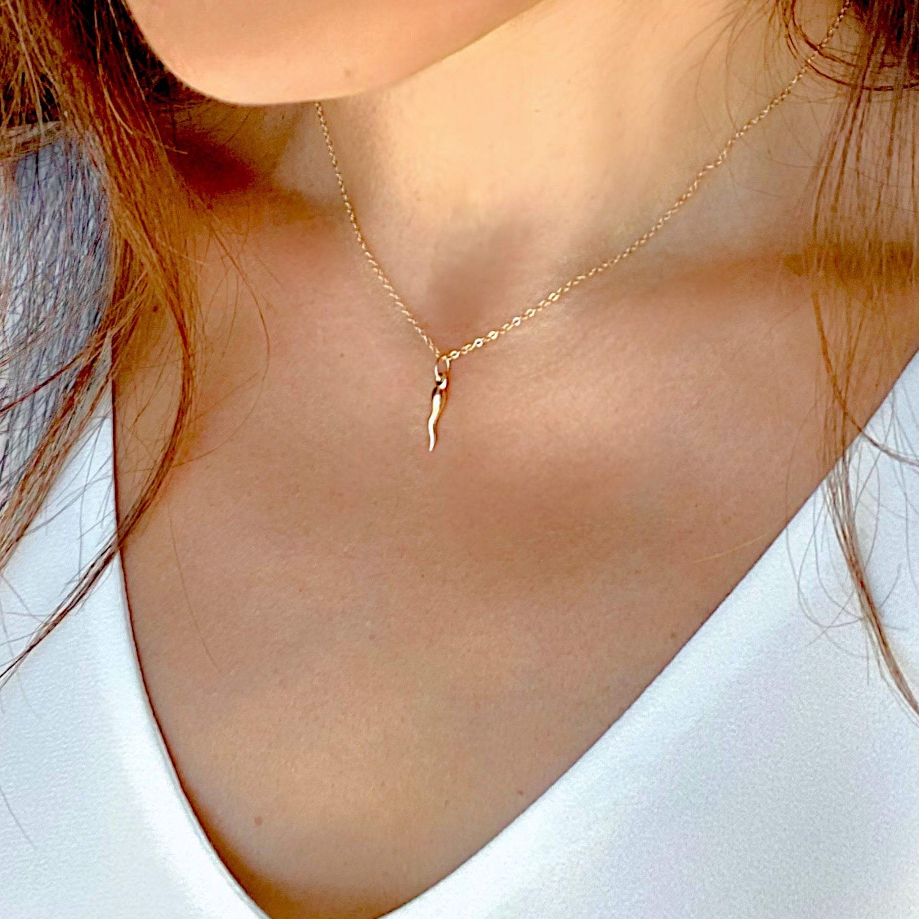 Model wearing the small 14K gold filled cornicello horn pendant necklace as a dainty minimalist daily layer.