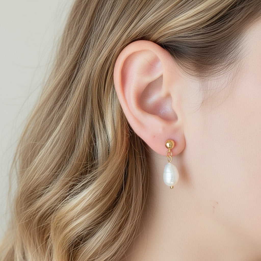 Model wearing 1-inch gold ball stud earrings with dangling freshwater baroque pearls