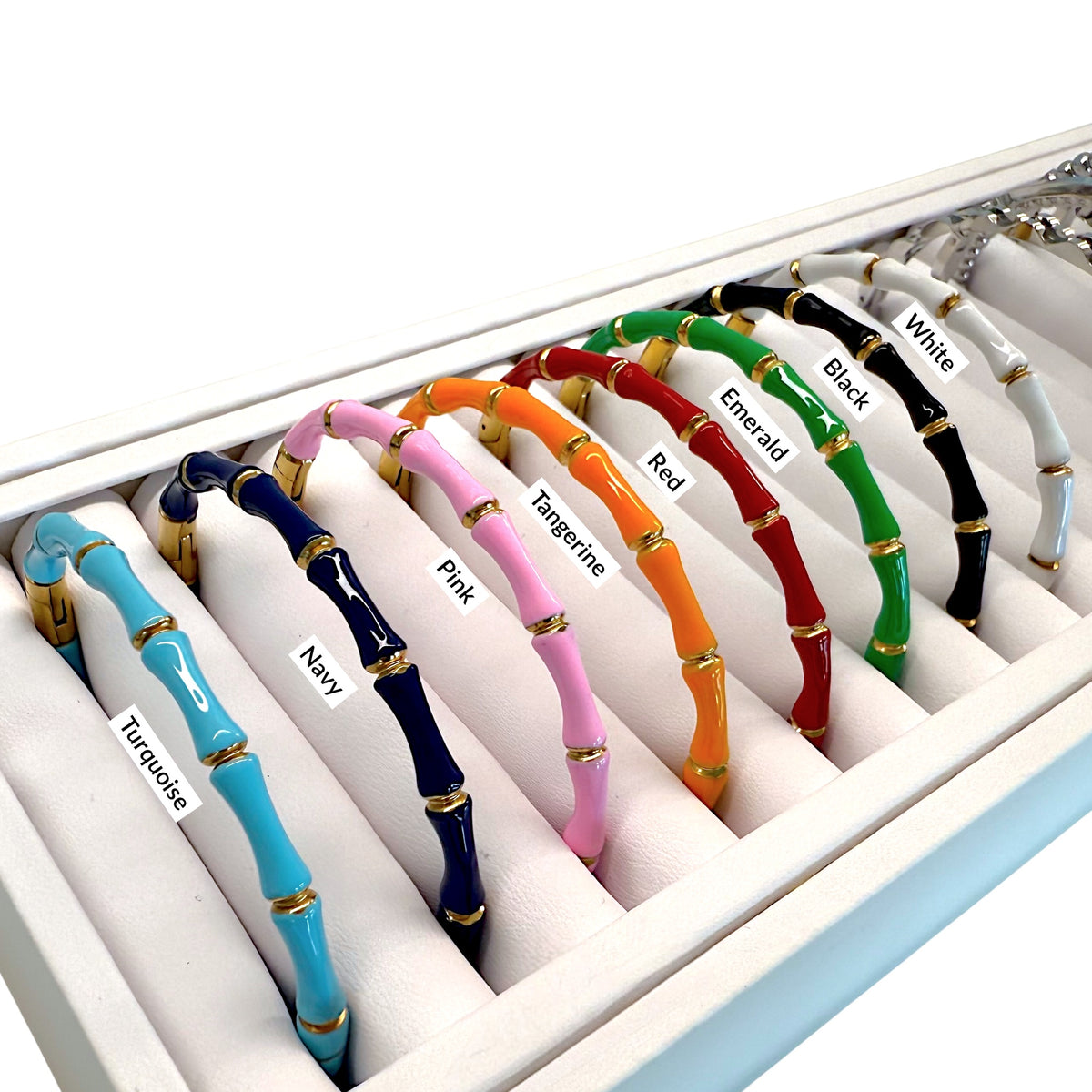 Full collection of gold bamboo enamel bangle bracelets displayed in a jewelry tray.