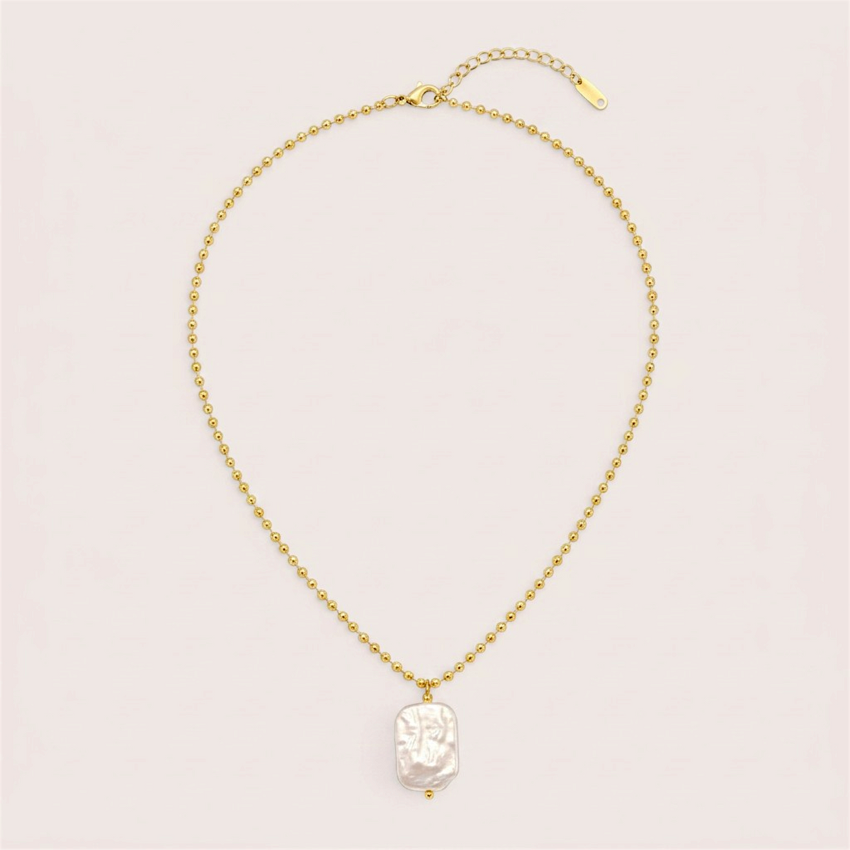 Full gold ball chain necklace laid flat with a white baroque pearl pendant, lobster clasp, and extension chain.