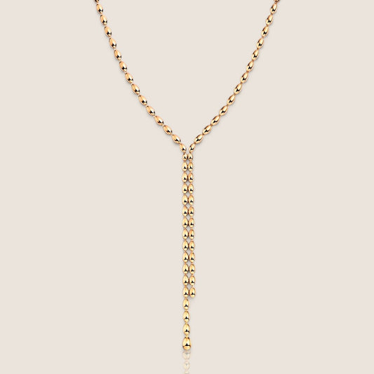 Gold oval beaded lariat necklace showing the Y-shaped junction and two unequal-length drops on a light background