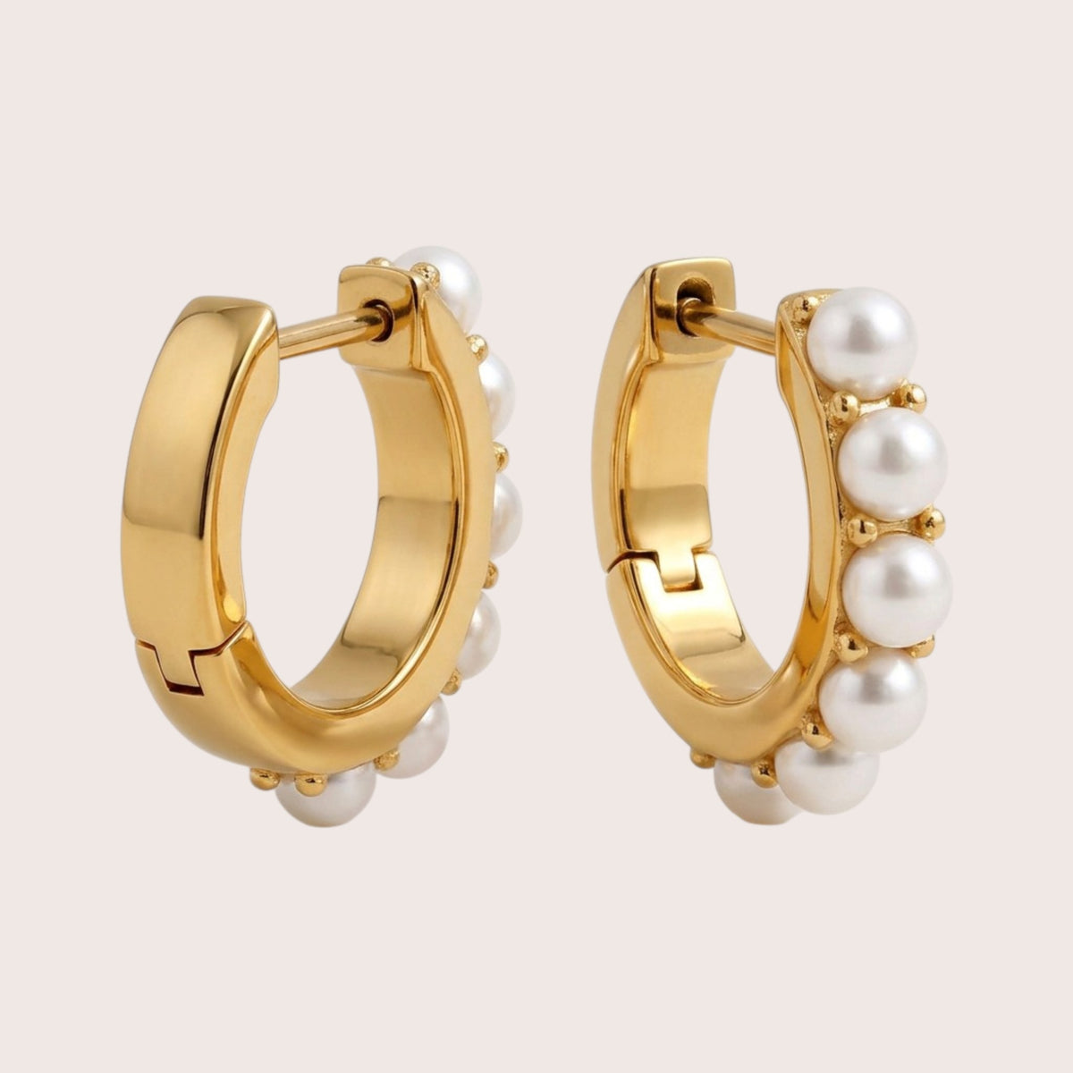 Gold pearl huggie hoops viewed from behind and at an angle, showing the polished gold backs, hinges, and pearl settings.