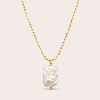 Gold ball chain necklace with an irregular rectangular freshwater pearl pendant on a warm neutral background.