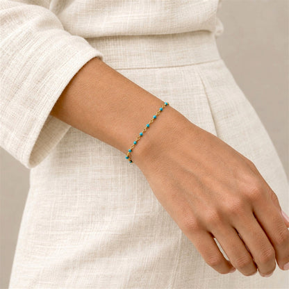 Delicate turquoise rosary chain bracelet worn alone on a wrist beside a denim 